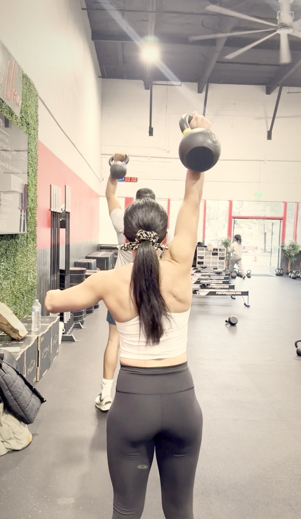Thais empurrando um kettlebell acima da cabeça